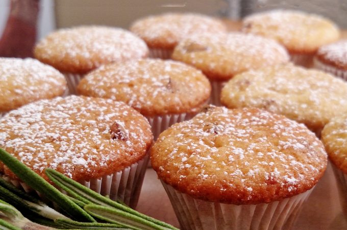 Close up of Orange Cranberry Muffins with powered sugar, rosemary