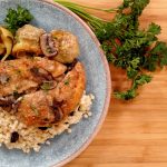 Chicken, Artichokes and mushrooms on a blue plate on bamboo cutting board with parsley