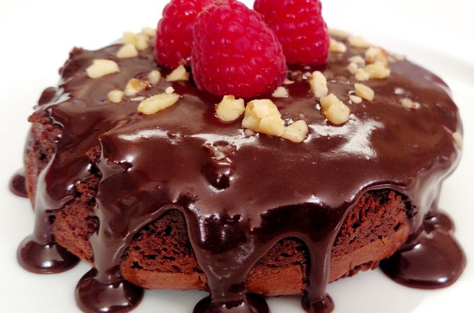 Flourless Chocolate Cake with Ganache, chopped nuts and raspberries on a white plate