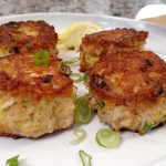 food network award winning crab cakes on a white plate with green onion garnish