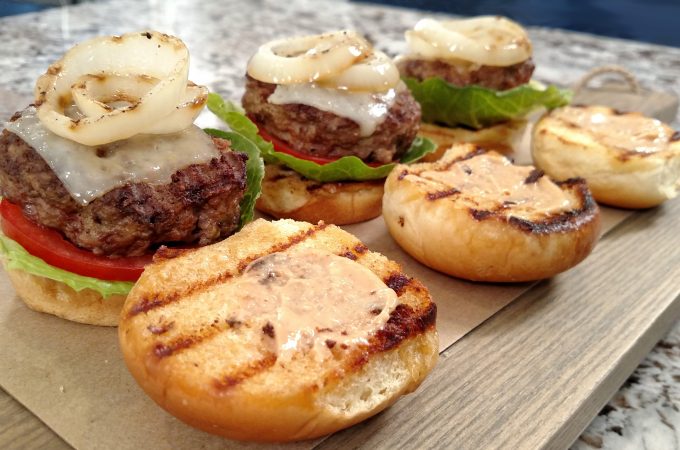 Hamburger Sliders on a wood cutting board, grilled onions, cheese