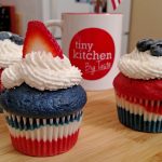 Red, White and Blue Velvet Cupcakes with Buttercream frosting, blueberries and strawberries with a Tiny Kitchen Big Taste coffee mug