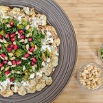 Roasted Cauliflower with Parsley, pomegranate seeds, olives, mint and feta cheese on a brown plate
