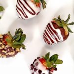 A variety of Chocolate Covered Strawberries on a White Plate. White Chocolate, Dark Chocolate. Chocolate Chips, Chopped Nuts, Espresso