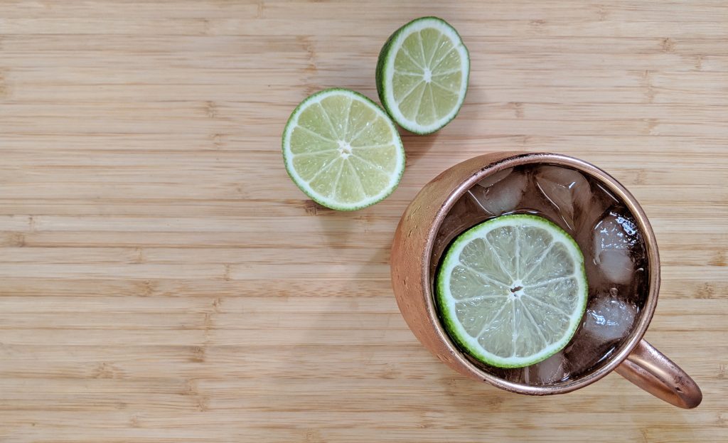 Overhead view of a Moscow Mule in a copper mug with a cut lime on a bamboo cutting board