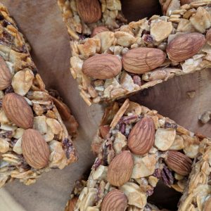 Overhead shot of Tiny Kitchen Zip Bars (Keto Granola Bars) with Almonds, Coconut, Sunflower Seeds, Pecans stacked on a wooden board